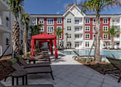 Thumbnail 44 of 48 - A red gazebo is situated in the middle of a courtyard with a pool.