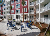 Thumbnail 47 of 48 - A patio area with chairs and tables in front of a red and white building.