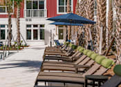Thumbnail 41 of 48 - A row of wooden chairs with green cushions are lined up on a patio.