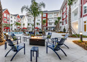 Thumbnail 46 of 48 - A patio with chairs and a fire pit in front of a building.