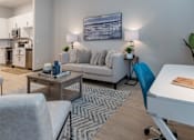 Thumbnail 10 of 48 - A modern living room with a grey couch, a coffee table, and a white desk.