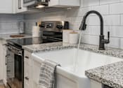 Thumbnail 5 of 48 - A kitchen with a granite countertop and a modern faucet.
