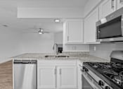 Thumbnail 14 of 43 - A kitchen with a stove, sink, and microwave.
