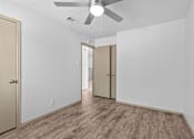 Thumbnail 29 of 43 - A room with a ceiling fan and wood flooring.