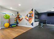 Thumbnail 17 of 28 - a workout room with a large green ball on the floor and a colorful geometric mural on the