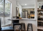 Thumbnail 3 of 28 - a kitchen with a breakfast bar and stools next to a large window with blinds