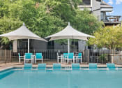 Thumbnail 14 of 17 - a swimming pool with blue chairs and umbrellas next to a resort pool