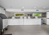 Thumbnail 12 of 17 - a kitchen with white cabinets and a counter with chairs