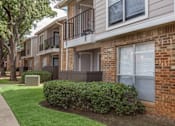 Thumbnail 14 of 24 - A row of apartment buildings with green bushes in front.