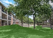 Thumbnail 16 of 24 - A grassy area in front of apartment buildings.