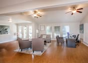 Thumbnail 18 of 24 - A spacious living room with a ceiling fan and a desk with a computer.