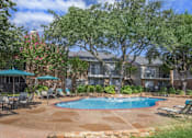 Thumbnail 6 of 24 - A pool surrounded by chairs and trees in front of a house.