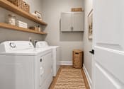 Thumbnail 12 of 33 - A laundry room with a washer and dryer, a basket, and a cabinet.