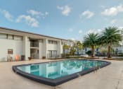 Thumbnail 16 of 18 - a swimming pool in front of a building with palm trees