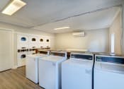 Thumbnail 15 of 18 - a laundry room with four washers and dryers and a door to a closet