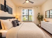 Thumbnail 5 of 30 - A bedroom with a large bed, a ceiling fan, and a window with blinds.