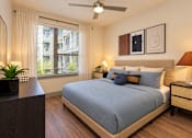 Thumbnail 3 of 30 - A bedroom with a bed, nightstand, and a ceiling fan.
