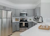 Thumbnail 19 of 39 - A modern kitchen with a stainless steel refrigerator and a wooden tray with tea cups on the counter.