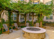 Thumbnail 14 of 22 - a fire pit with two chairs and a pergola in front of a building