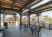 Thumbnail 30 of 30 - A patio with a table and chairs under a roof.