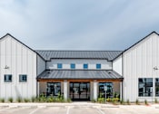 Thumbnail 2 of 30 - A modern building with a black roof and white walls.