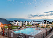 Thumbnail 3 of 30 - A large outdoor swimming pool surrounded by a fence and a wooden pergola.