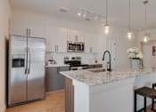 Thumbnail 3 of 38 - A modern kitchen with a stainless steel refrigerator and a marble countertop.