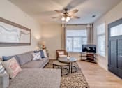 Thumbnail 5 of 30 - A living room with a grey couch, a coffee table, and a ceiling fan.
