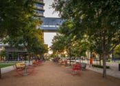 Thumbnail 28 of 30 - a park with red and yellow chairs and a walkway in the background