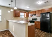 Thumbnail 4 of 21 - A kitchen with a black refrigerator and wooden cabinets.