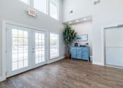 Thumbnail 14 of 29 - A room with a white wall and a wooden floor with a blue cabinet and a plant.