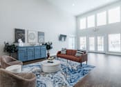 Thumbnail 10 of 29 - A living room with a blue rug and a brown sofa.