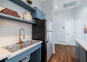 Thumbnail 13 of 29 - A kitchen with a black refrigerator and a white sink.