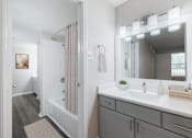 Thumbnail 10 of 62 - A bathroom with a sink, mirror, and shower.