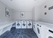 Thumbnail 46 of 62 - A laundry room with a row of washing machines.