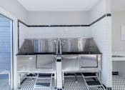 Thumbnail 42 of 62 - A clean, empty commercial kitchen with stainless steel appliances and white tiled walls.