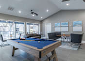 Thumbnail 33 of 62 - A pool table is in the middle of a room with a couch, chair, and television.