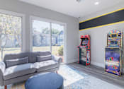 Thumbnail 31 of 62 - A grey couch sits in a living room with a vintage arcade machine.