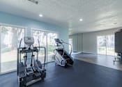 Thumbnail 39 of 62 - A spacious home gym with a treadmill, elliptical trainer, and a stationary bike.