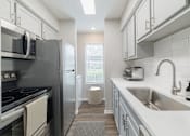 Thumbnail 3 of 62 - A modern kitchen with a stove, refrigerator, and sink.