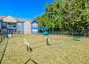 Thumbnail 59 of 62 - A dog park with a blue fence and a green bench.