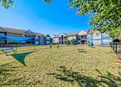 Thumbnail 57 of 62 - A sunny day at the park with a blue sky and apartment buildings in the background.