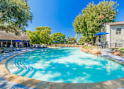 Thumbnail 51 of 62 - A large outdoor swimming pool surrounded by trees and a building.