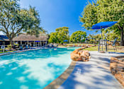 Thumbnail 52 of 62 - A swimming pool surrounded by trees and a blue umbrella.