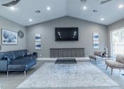 Thumbnail 28 of 62 - A living room with a blue sofa, a black coffee table, and a television mounted on the wall.