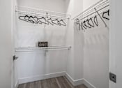 Thumbnail 21 of 35 - A white closet with clothes hanging on hangers.