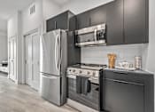 Thumbnail 27 of 35 - A modern kitchen with stainless steel appliances and black cabinets.