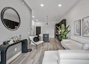 Thumbnail 29 of 35 - A modern living room with a white couch, a round mirror, and a wooden floor.