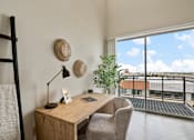 Thumbnail 28 of 35 - A room with a desk and chair with a window overlooking a balcony.