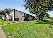 Thumbnail 19 of 23 - A white building with a brown roof is surrounded by a green lawn.